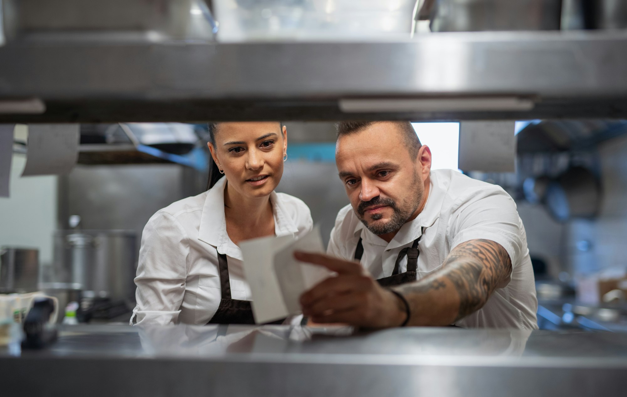 Chef and cook taking order slip in commercial kitchen